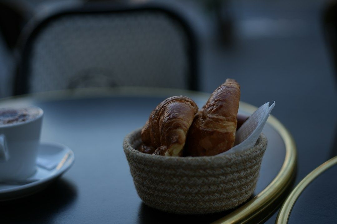 Kurv med croissanter ved siden af en kaffekop på et bord